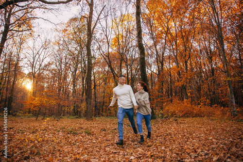 cheerful couple runs in the autumn park. covered with yellow foliage. Autumn walk in the fresh air. Two lovers in an autumn park. Romantic dates © Ivan