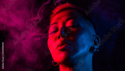 Sensual portrait of asian woman with short haircut smoking in neon light. 