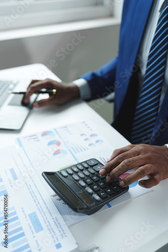 A male accountant or a business man uses a laptop to calculate investment results. And making financial reports on the desk Business finance accounting concept