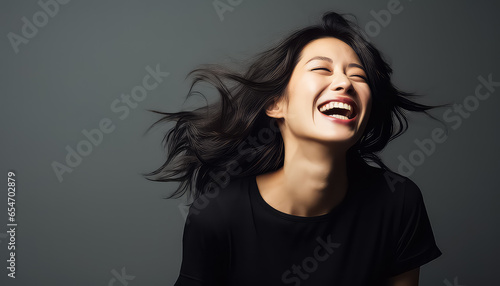 Smiling asian woman with wind in her black hair in studio photo