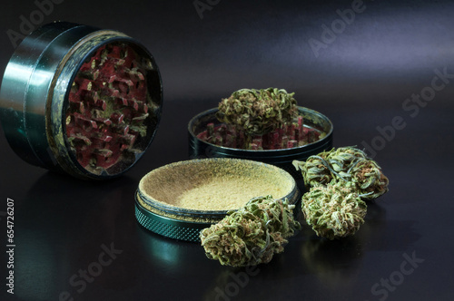 Fotografie herb grinder full of cannabis pollen surrounded by dry flowers of medical mariju