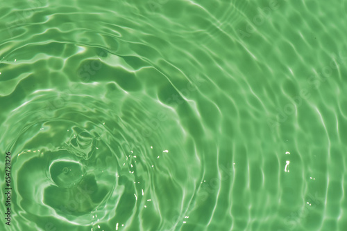 Defocus blurred transparent green colored clear calm water surface texture with splashes reflection. Trendy abstract nature background. Water waves in sunlight with copy space. Blue watercolor shine.