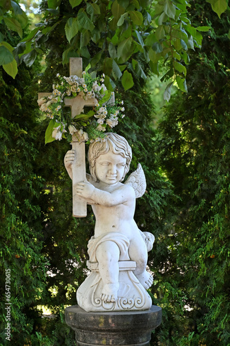 A statue of an angel with a cross in an old cemetery.