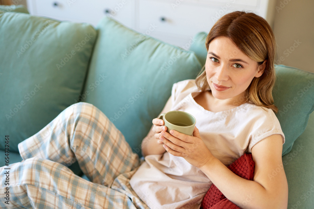 An attractive young woman relaxing at home drinking coffee in pyjamas An attractive young woman relaxing at home drinking coffee in pyjamas