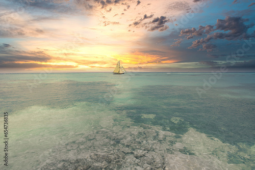 Panoramic view from the shoreline of a sailing ship sailing at sunrise in the South Seas. In the background the multicolored sky of French Polynesia.
