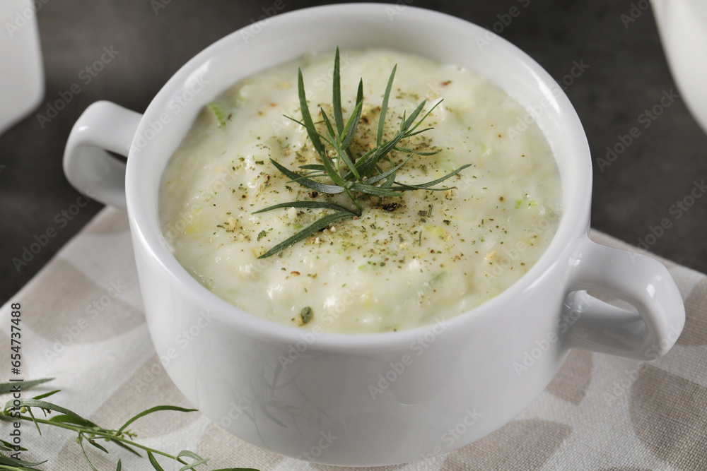 Delicious cream soup with tarragon, spices and potato in bowl on table, closeup Delicious cream soup with tarragon, spices and potato in bowl on table, closeup