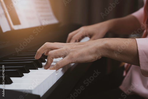 Close up senior woman hand playing electronic paino at home, relaxing time with music, practice music, learning music at home with light at the coner.