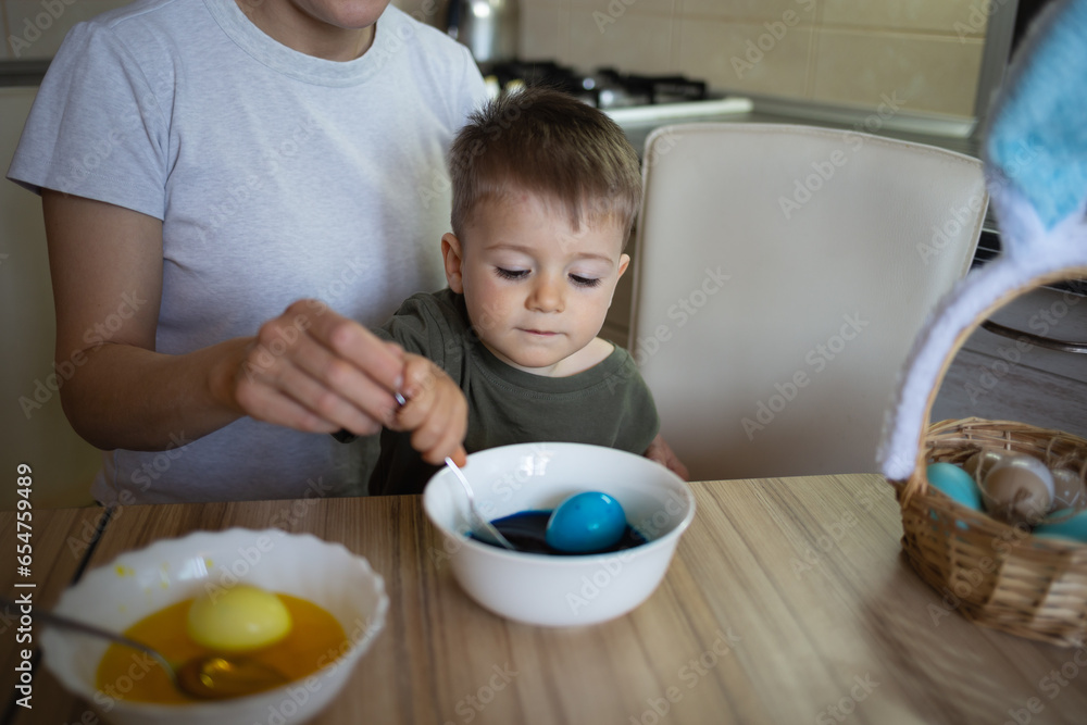 little cute boy paints eggs for easter sitting in the kitchen at the table little cute boy paints eggs for easter sitting in the kitchen at the table