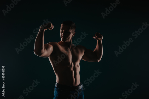 Silhouette photo of strong man showing his biceps and proudly looking at them. Sport motivation concept © qunica.com