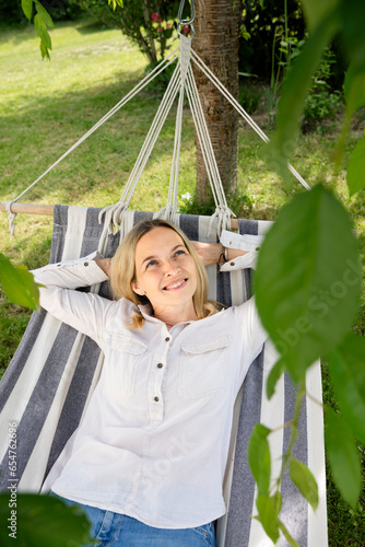 beautiful, blond young woman is relaxing in hammock in garden