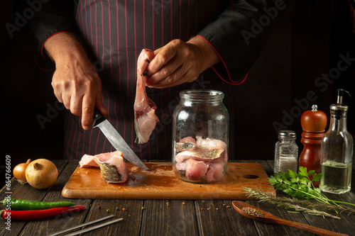 Cutting raw carp fish for preparing herring in a jar or canning. Knife in the hand of the cook and steak with fish. Fish diet concept photo