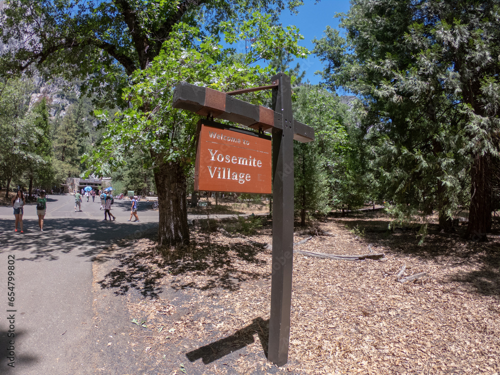 Yosemite Valley, California, USA, June 27, 2022: A wooden sign indicating the entrance to Yosemite Village in Yosemite National Park, CA.