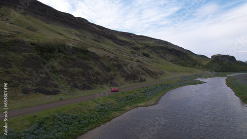 4X4 car driving on a country road in Þjórsardalur valley, along the river Þjorsa, Holtasoley flowers field, nearby the Burfell (Pjorsardal) and Hekla volcano in Iceland. photo