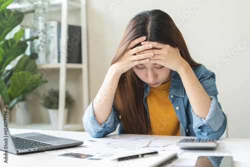 Financial owe asian woman sitting cover face with hands, stressed by calculate expense at home, looking at invoice or bill, have no money to pay, mortgage or loan. Debt, bankruptcy or bankrupt concept