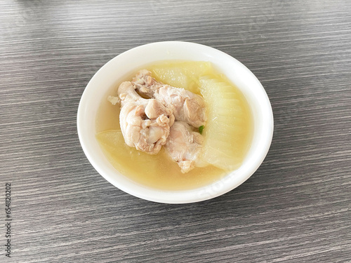 Clear soup with chicken and winter melon white bowl on wood