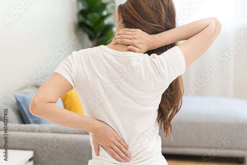 Pain body muscles stiff problem, asian young woman painful back, neck ache from work hand holding massaging rubbing shoulder hurt, sore sitting on bed while wake up at home. Health care and medicine. photo