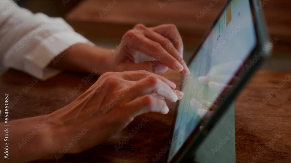 Close-up: female hands typing on a tablet screen in a cafe. Wrinkled fingers themselves touch the touchscreen in a coffee shop or restaurant. Grandma writes a message. Typing text, freelancer. Close-up: female hands typing on a tablet screen in a cafe. Wrinkled fingers themselves touch the touchscreen in a coffee shop or restaurant. Grandma writes a message. Typing text, freelancer.