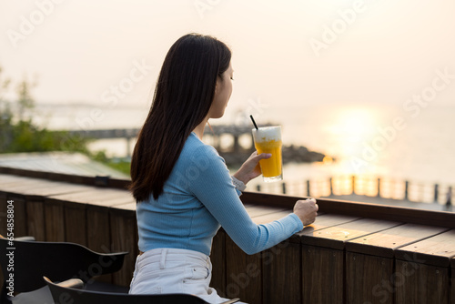 Woman drink cup of juicy at outdoor cafe under sunset © leungchopan