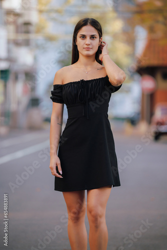 Portrait of pretty elegant woman in black dress at the autumn alley