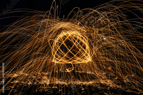 Long exposure, light painting photography. Fireworks in the night sky. Сurvy lines of vibrant neon metallic yellow gold against a black background. Space fantasy. Energy concept. Explosion effect.
