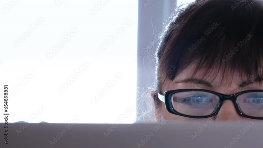 Focused Woman Working on Laptop: Close-up of Eyes, Browsing Online by the Window Focused Woman Working on Laptop: Close-up of Eyes, Browsing Online by the Window