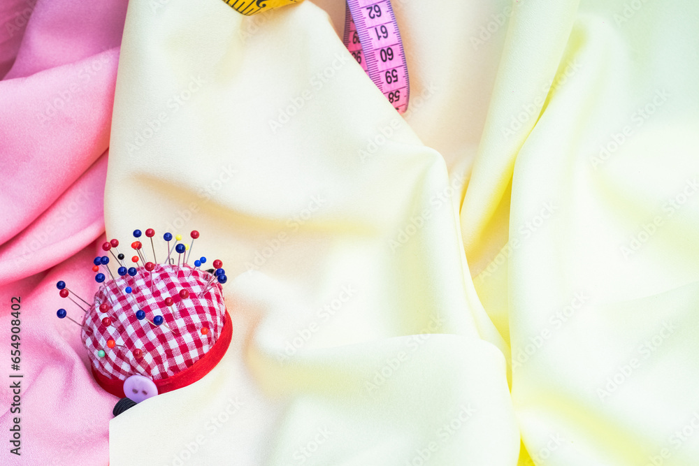 yellow and pink fabric with measure tape and red and red pin cushion yellow and pink fabric with measure tape and red and red pin cushion
