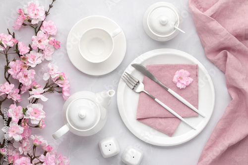 Breakfast concept, morning tea party. Spring flowers. White ceramic tableware and cutlery. Table setting with empty plate, teapot, cup, fork and knife. Romantic still life, floral decor.