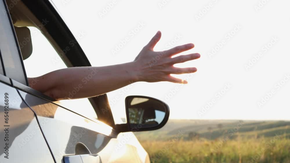 Hand in sun. Concept car travel on the road. Young girl stretches her ...