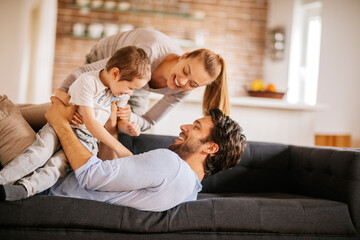Happy young family bonding and having fun on the couch at home