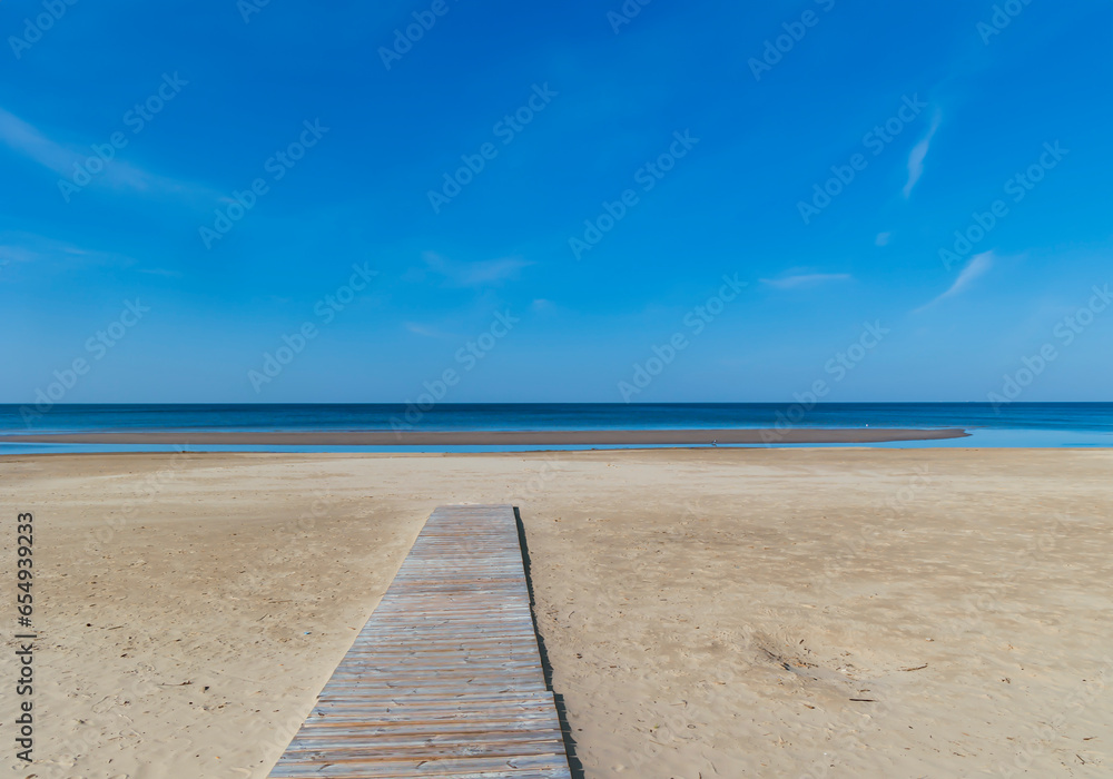 Wooden deck along the sandy beach leading to the deserted shore of the Baltic Sea in Jurmala, Latvia. The concept of natural minimalism.