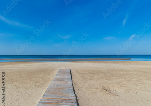 Wooden deck along the sandy beach leading to the deserted shore of the Baltic Sea in Jurmala, Latvia. The concept of natural minimalism.