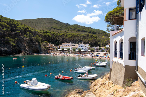 Fototapeta Naklejka Na Ścianę i Meble -  Image of a small beach discovered along the coastal path (Camí de Ronda), featuring small white houses and boats parked at the entrance.