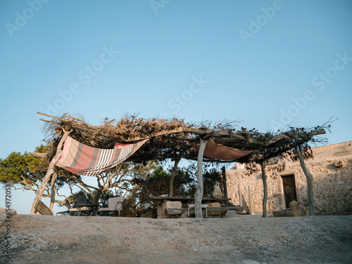 A fisherman house solitude on a rock, observing the surroundings at a peaceful recreational area near Sa Rapita, Mallorca, with house in the distance photo