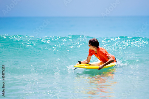 Photography Child surfing on tropical beach. Surfer in ocean.