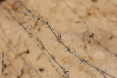 Barbed wire on sand background close-up