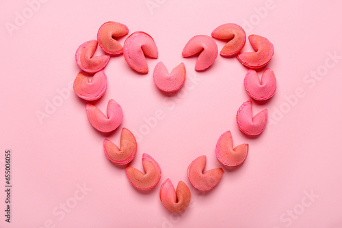 Heart made of fortune cookies on pink background photo