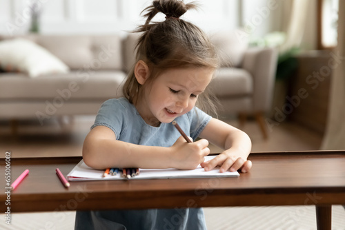 Smart little girl sit on floor at home drawing in album, cute small preschooler kid painting picture with colorful pencils, enjoy leisure activity on weekend, children development, education concept