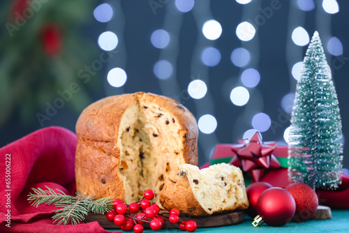 Cut Panettone with Christmas decor on table against blurred lights