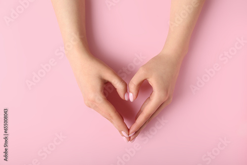 Fototapeta Naklejka Na Ścianę i Meble -  Woman making heart with her hands on pink background