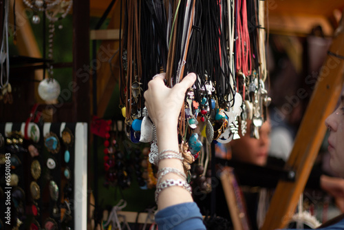 Celebrating the Tbilisoba holiday. Day of city Tbilisi, Georgia. Street fair. Female hand with metal silver bracelets. Woman choosing new authentic jewelry as birthday gift at folk craft festival