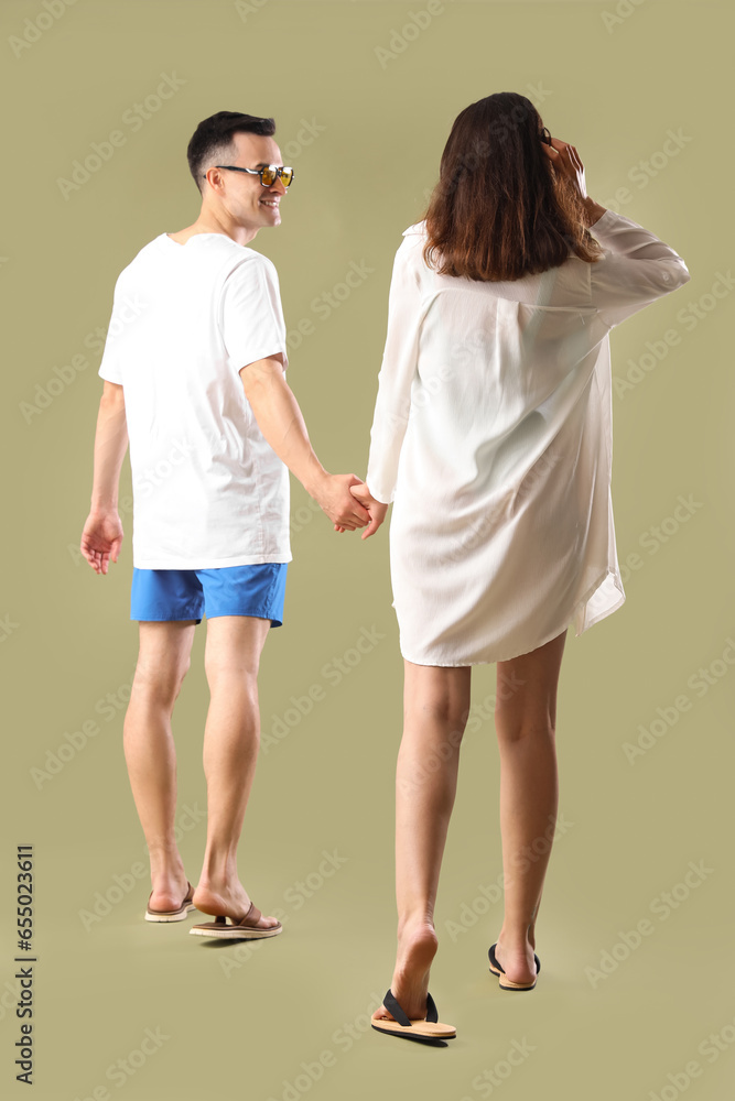 Young couple in summer clothes on green background, back view
