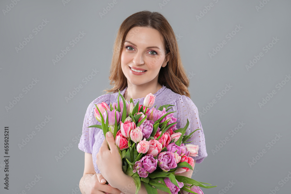 Happy young woman with bouquet of beautiful tulips on grey background Happy young woman with bouquet of beautiful tulips on grey background