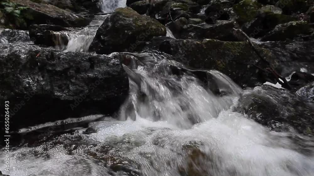 View of a waterfall in a mountain river with stones View of a waterfall in a mountain river with stones