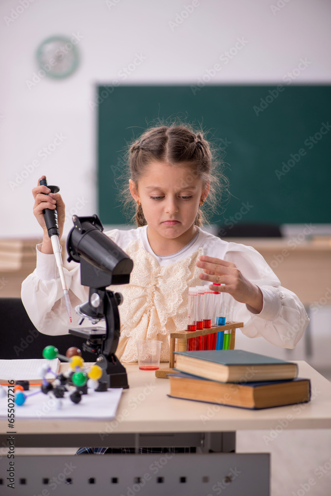 Small girl studying chemistry in the classroom