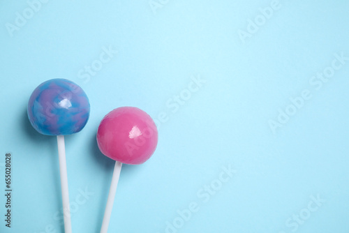Sticks with colorful lollipops on light blue background, flat lay. Space for text © New Africa