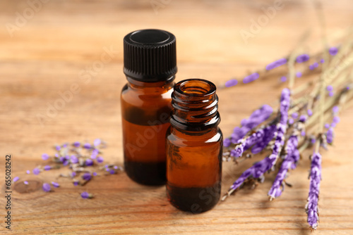 Fototapeta Naklejka Na Ścianę i Meble -  Essential oil and lavender flowers on wooden table, closeup