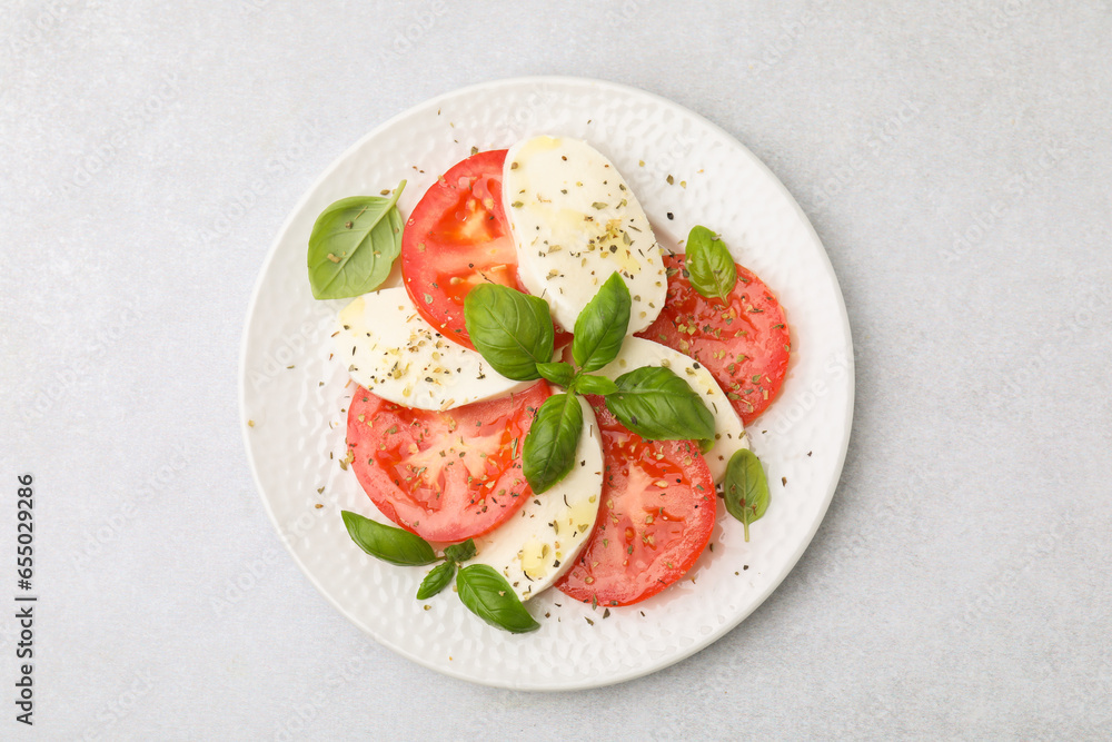 Plate of delicious Caprese salad with herbs on light grey table, top view Plate of delicious Caprese salad with herbs on light grey table, top view