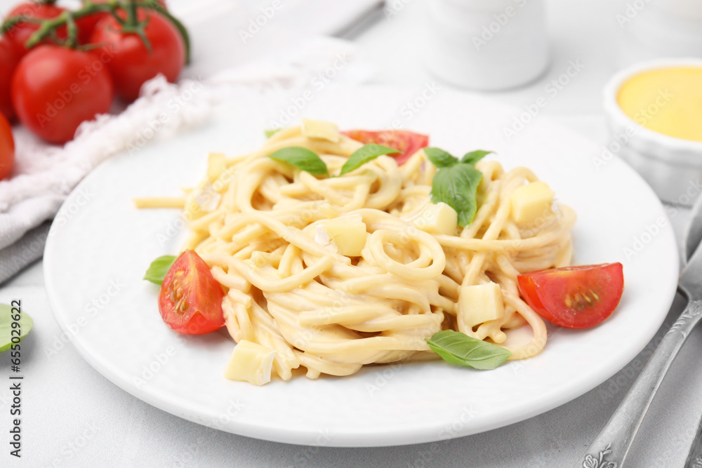 Delicious pasta with brie cheese, tomatoes and basil leaves on white table, closeup