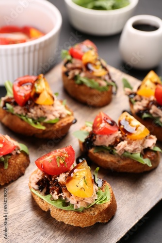 Delicious bruschettas with balsamic vinegar, tomatoes, arugula and tuna on grey table