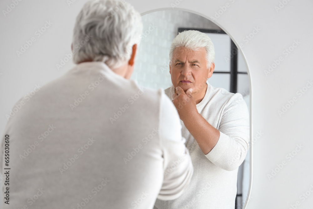 Senior man looking in mirror at home Senior man looking in mirror at home